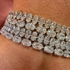 A close-up of a multi-row diamond bracelet worn on a wrist, featuring marquise-cut and oval diamonds set in yellow gold.