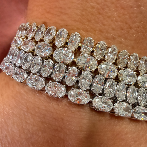 A close-up of a multi-row diamond bracelet worn on a wrist, featuring marquise-cut and oval diamonds set in yellow gold.