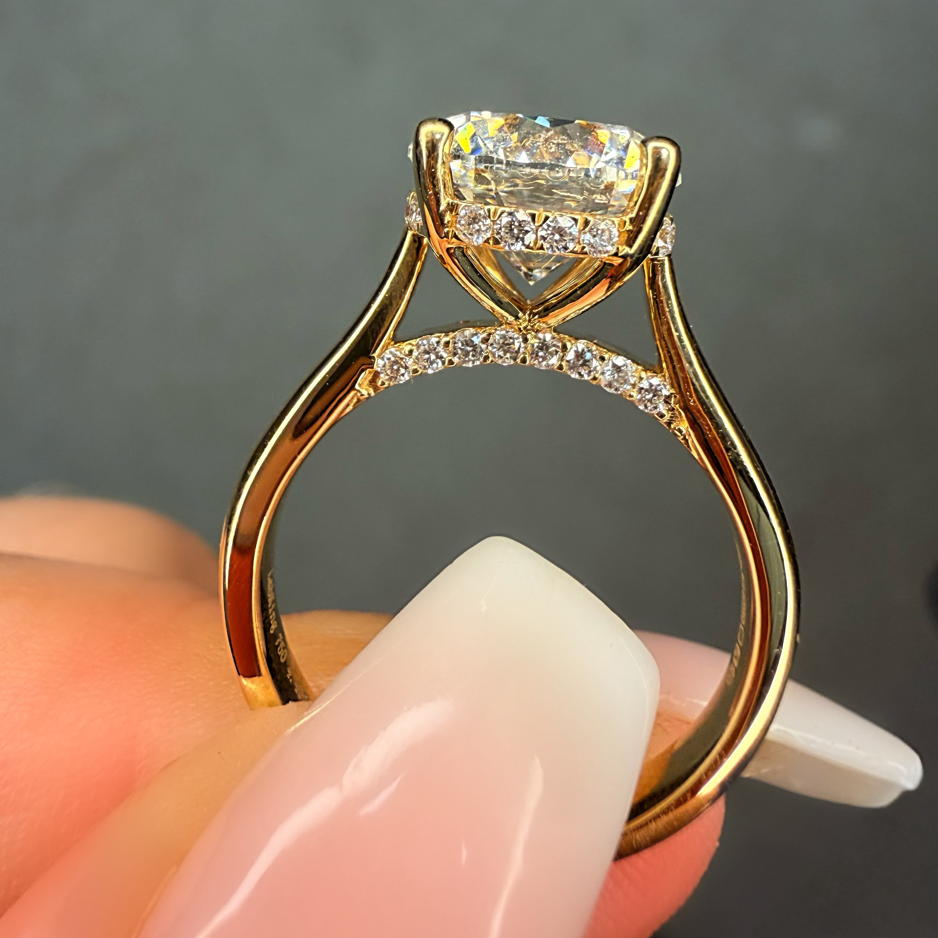 Gold ring with a heart-shaped diamond held by a hand against a dark background