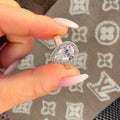 Hand holding a diamond ring with a patterned fabric background
