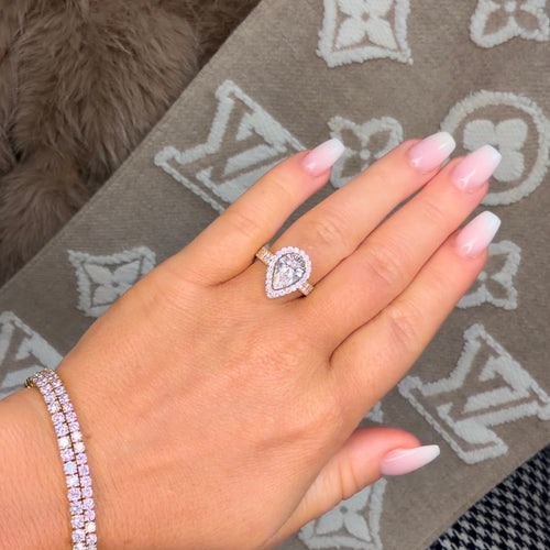 Hand wearing a ring with a diamond on a patterned fabric background
