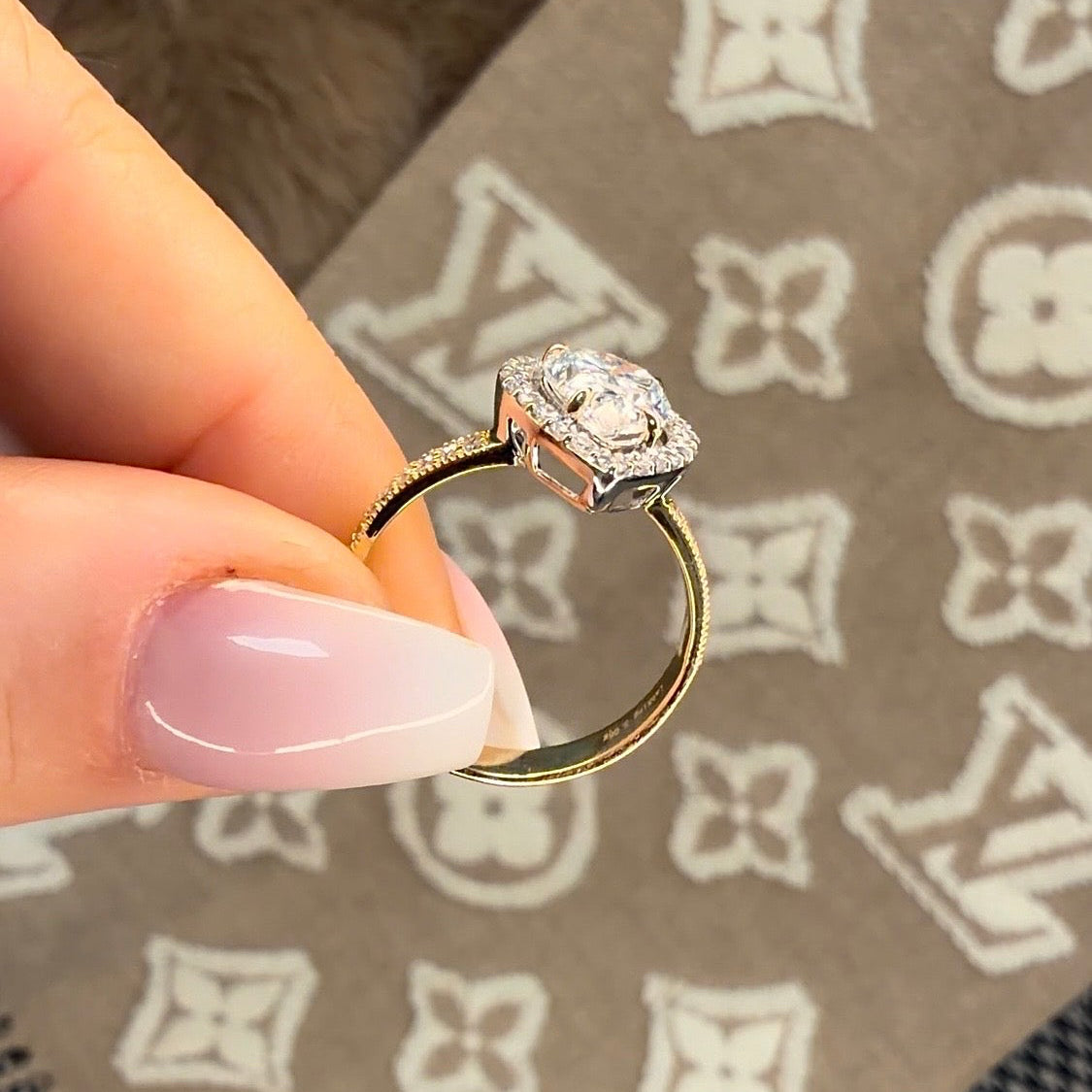 Gold ring with a diamond held by a hand on a patterned surface