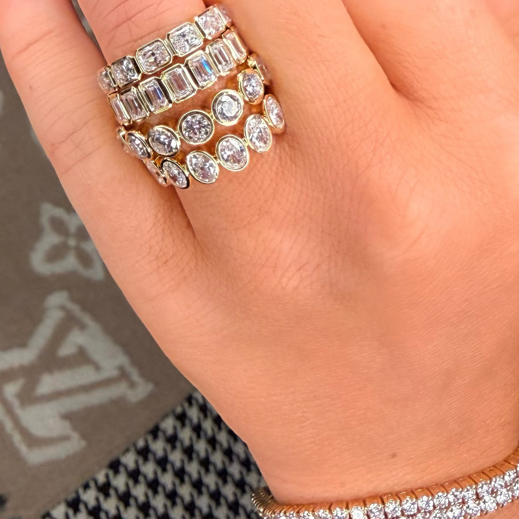 Close-up of a hand wearing multiple diamond rings on a blurred background