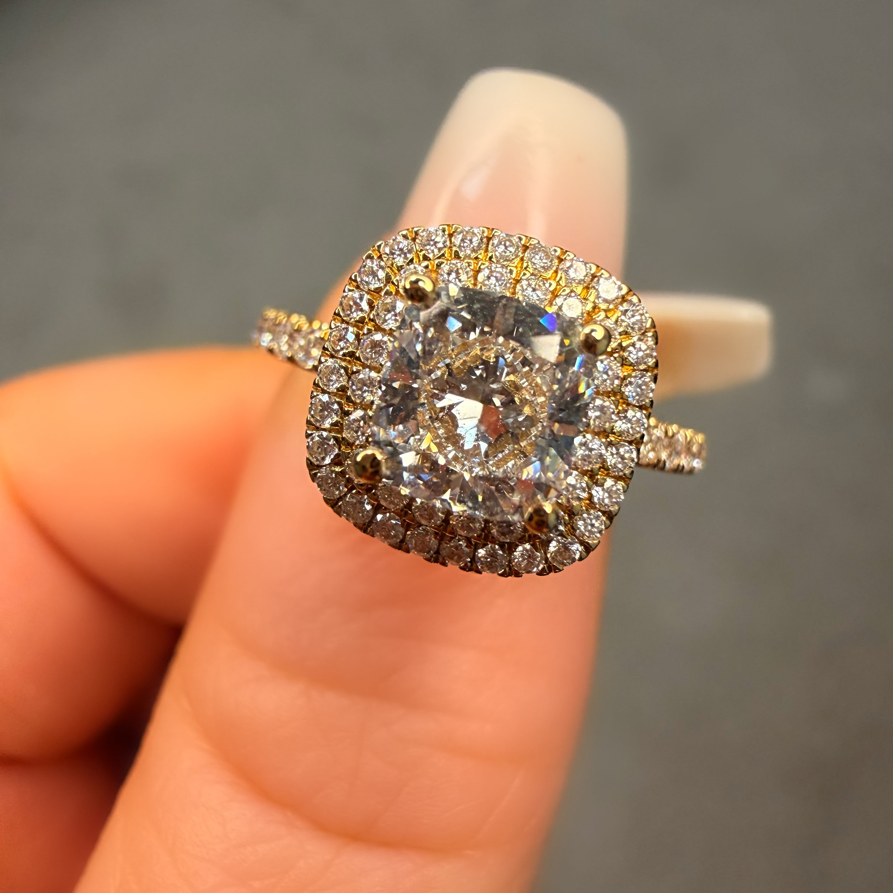 Diamond ring held on a finger against a neutral background