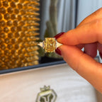 Gold ring held by a hand with a blurred background