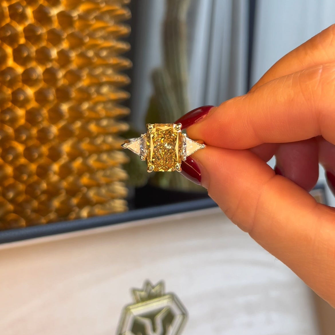 Gold ring held by a hand with a blurred background