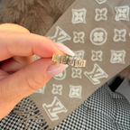 Gold ring held by a hand with a patterned fabric background