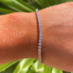 Gold bracelet on a wrist with a green leafy background