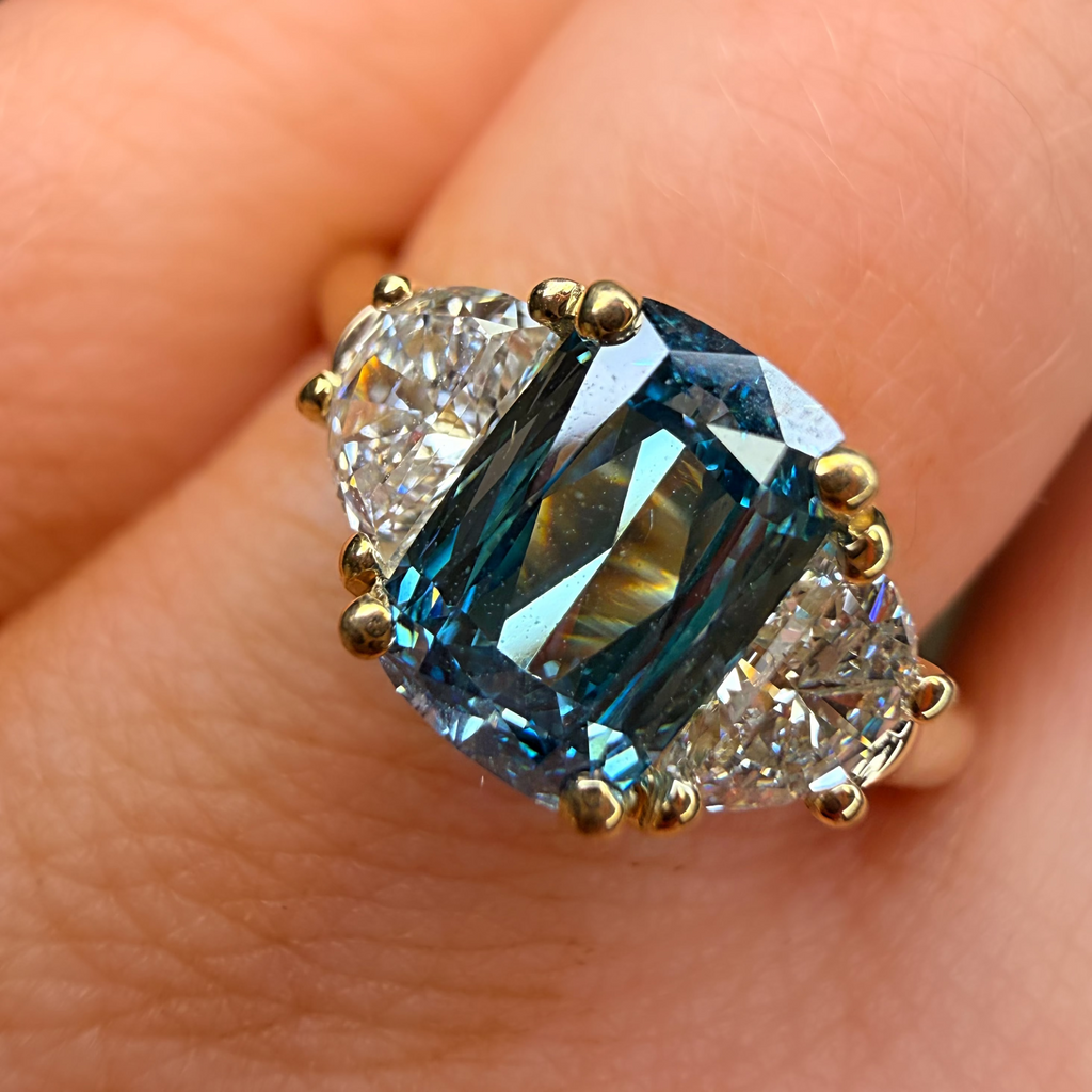 Gold ring with a blue gemstone on a person's finger