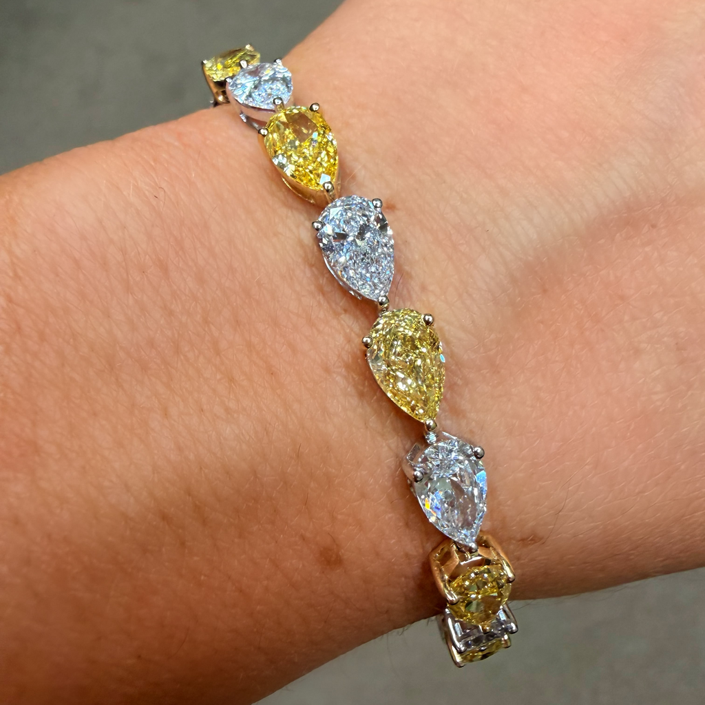 Bracelet with yellow and clear gemstones on a wrist against a neutral background