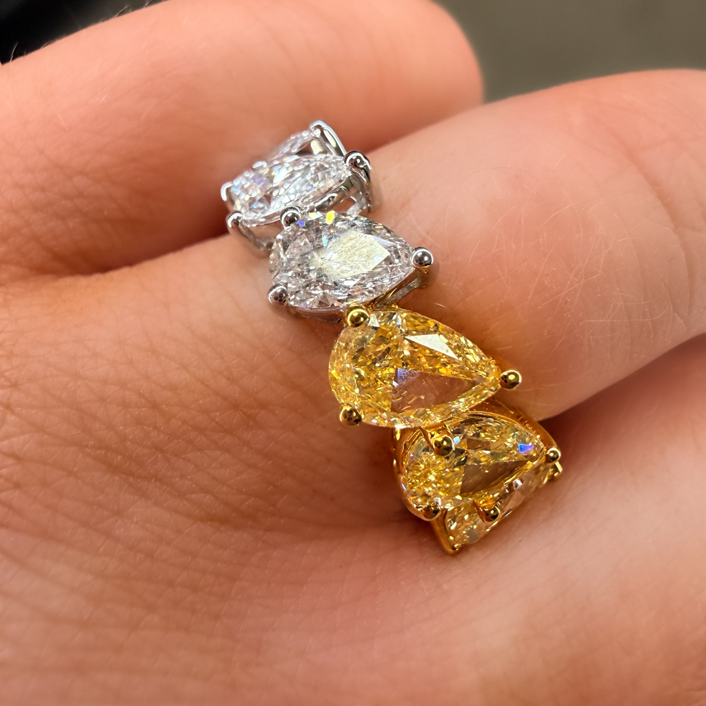 Two diamond rings being worn on fingers, one with yellow gemstones and the other with clear gemstones.