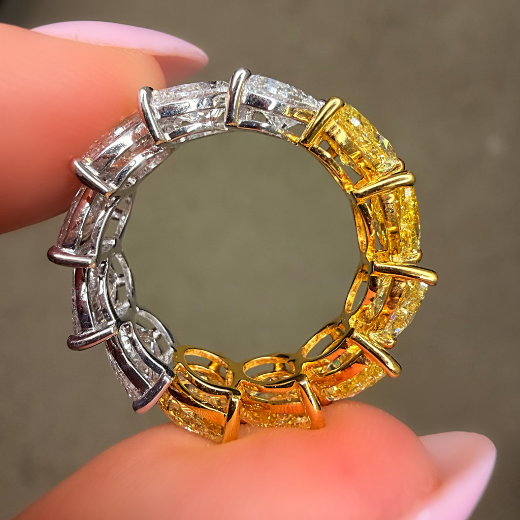 Gold and silver ring held between fingers against a neutral background
