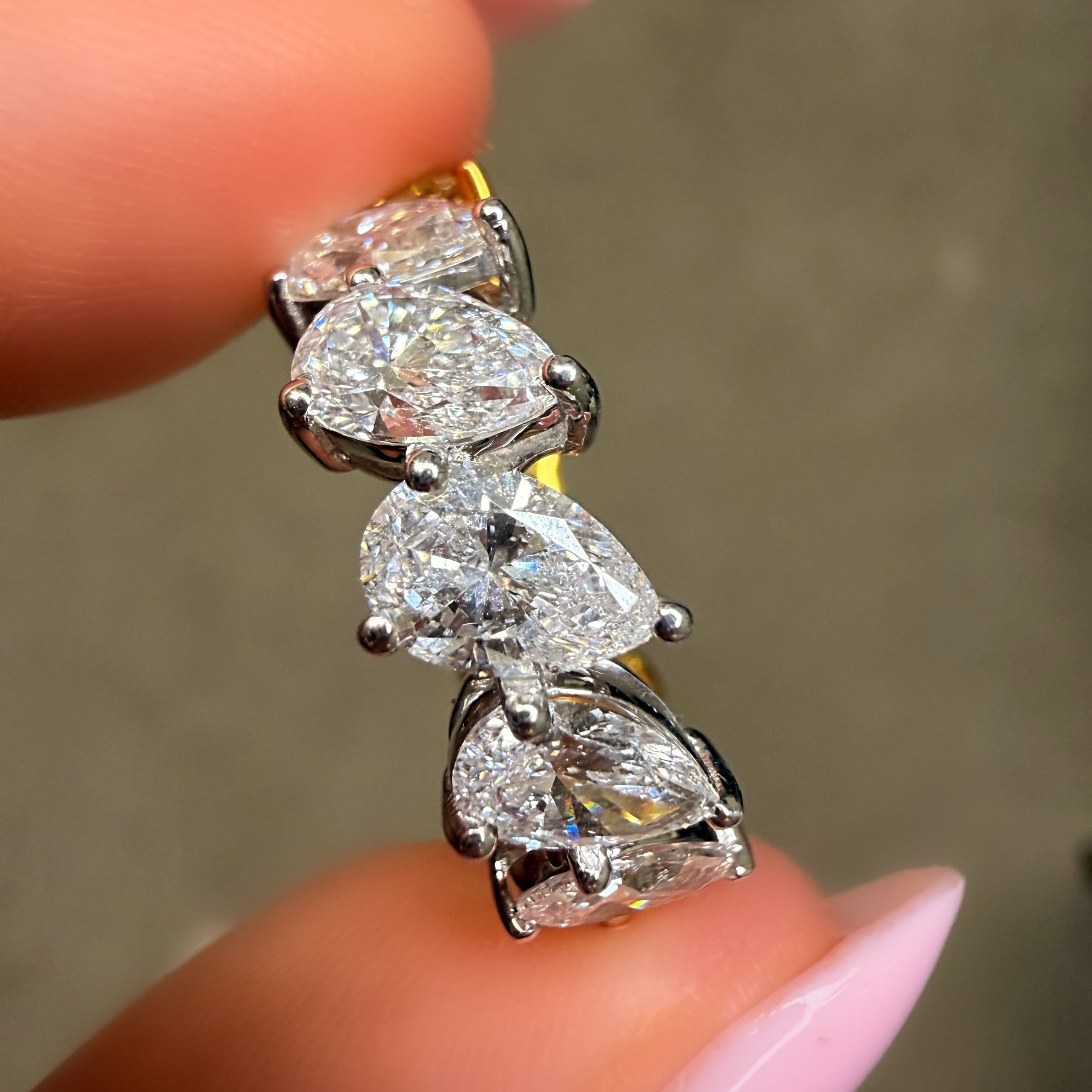 Diamond earring held between fingers with a neutral background