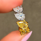 Gold and silver earring held between fingers against a neutral background