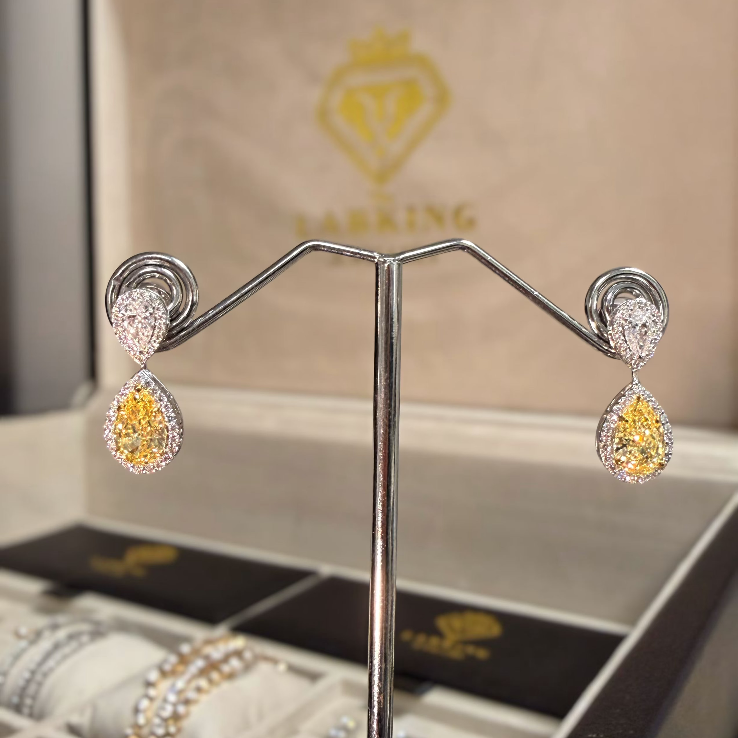 Pair of earrings on a stand with a Larking box in the background