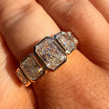 A close-up of a hand wearing a silver-toned ring with three large, textured clear stones in a row.