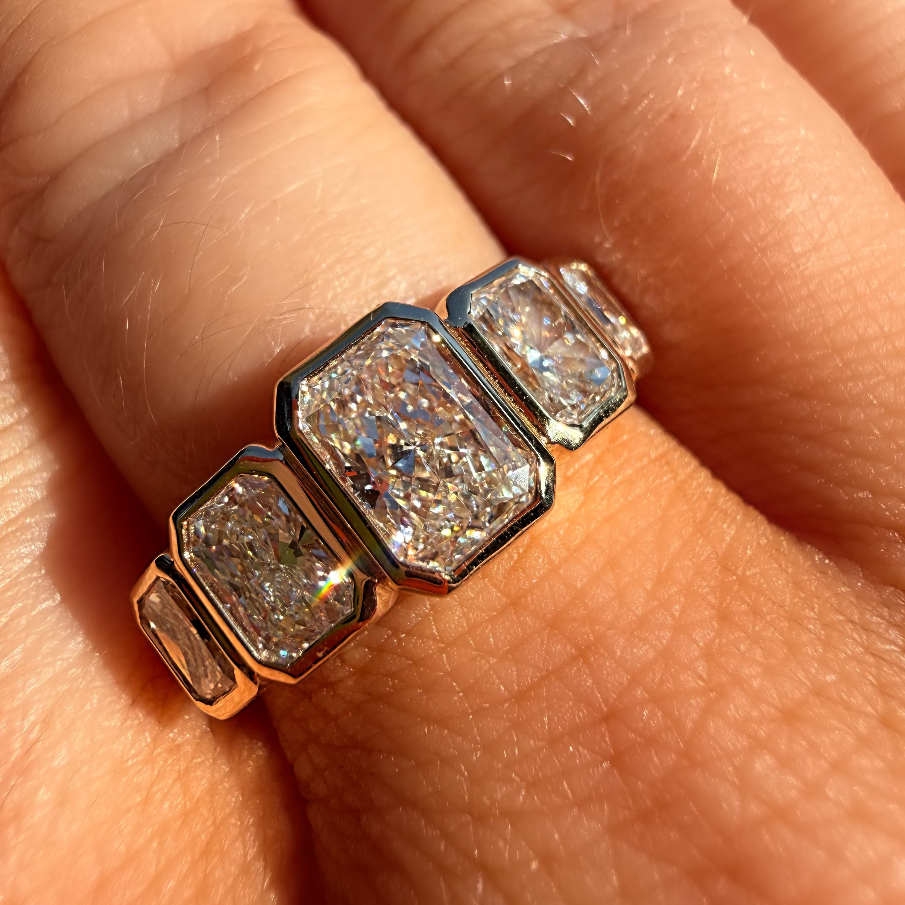 A close-up of a hand wearing a silver-toned ring with three large, textured clear stones in a row.