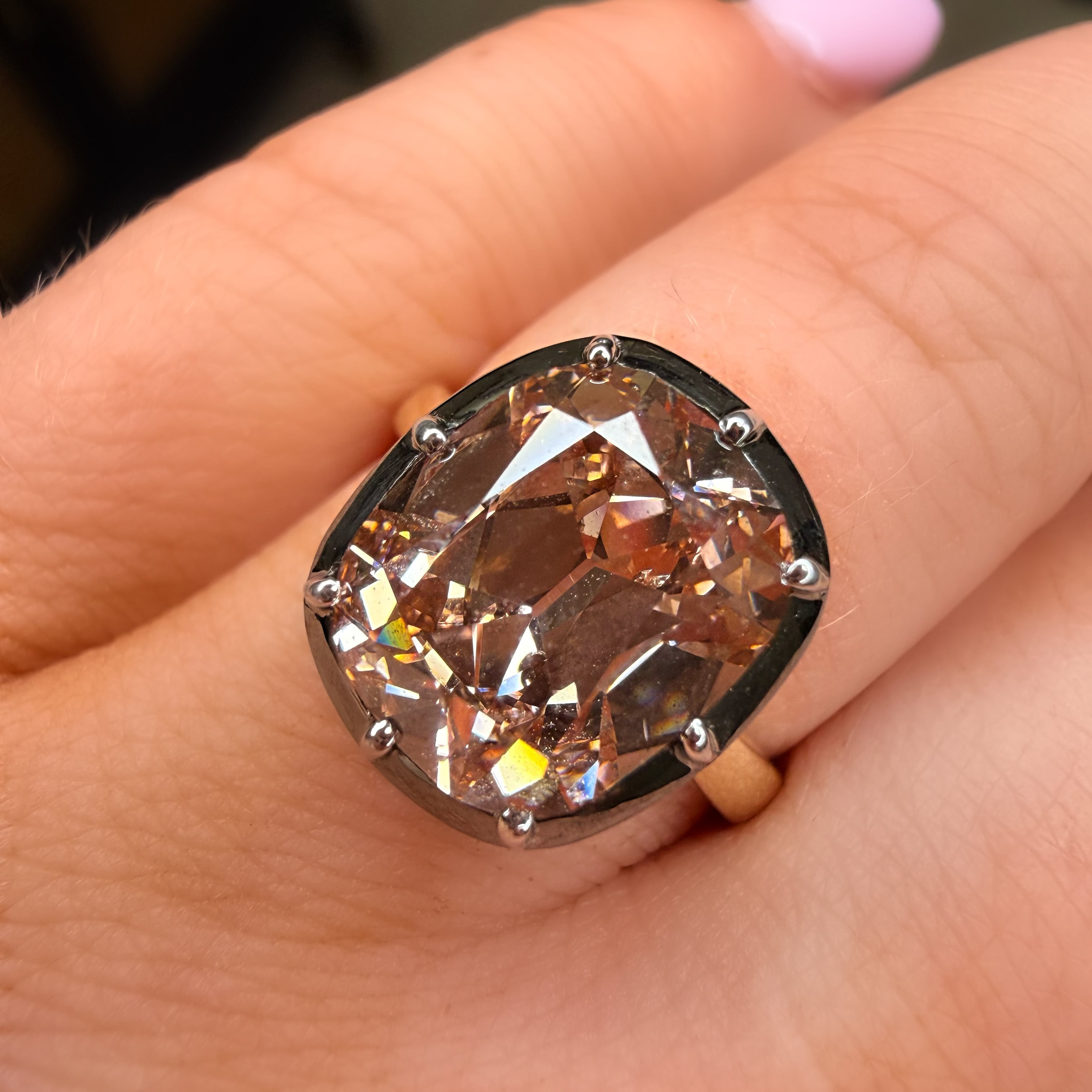 Ring with a large, faceted gemstone on a person's finger