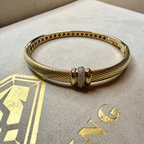 Gold bracelet with a decorative clasp on a branded box