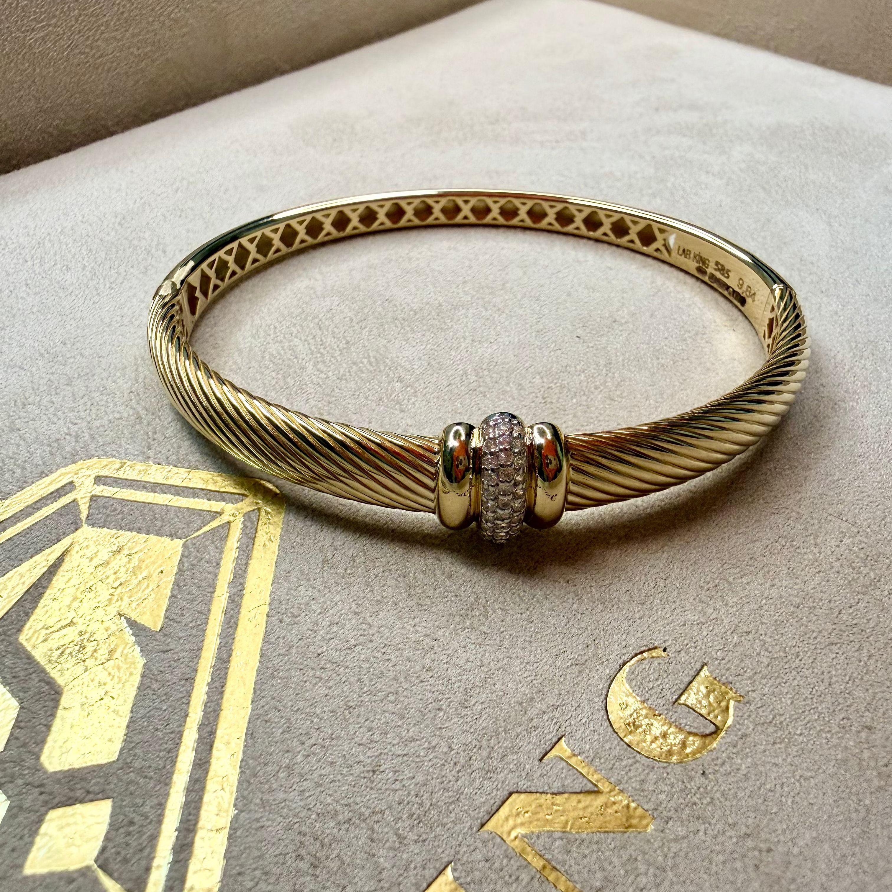 Gold bracelet with a decorative clasp on a branded box