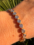 Gold bracelet with clear stones on a wrist against a natural background