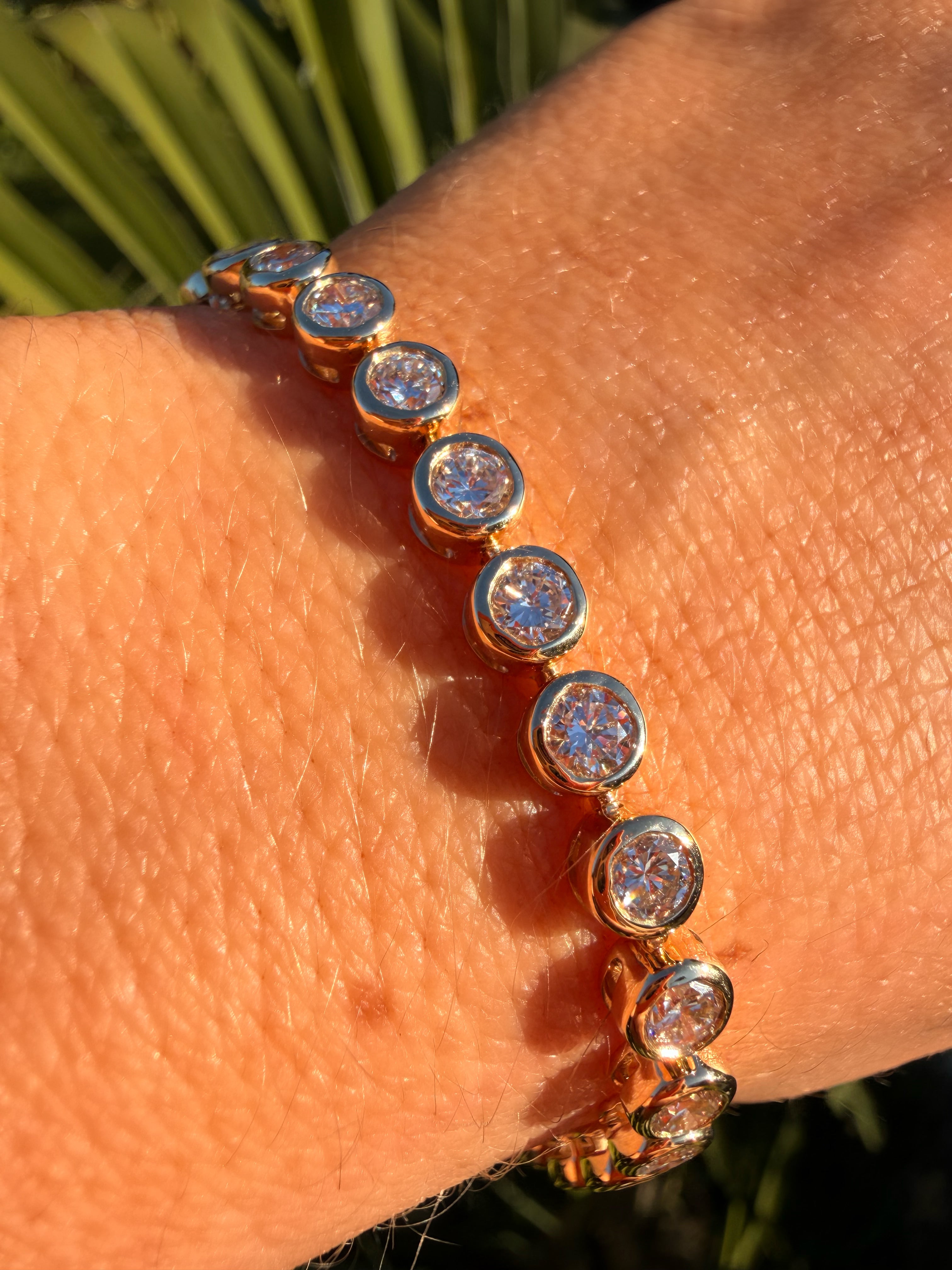 Gold bracelet with clear stones on a wrist against a natural background