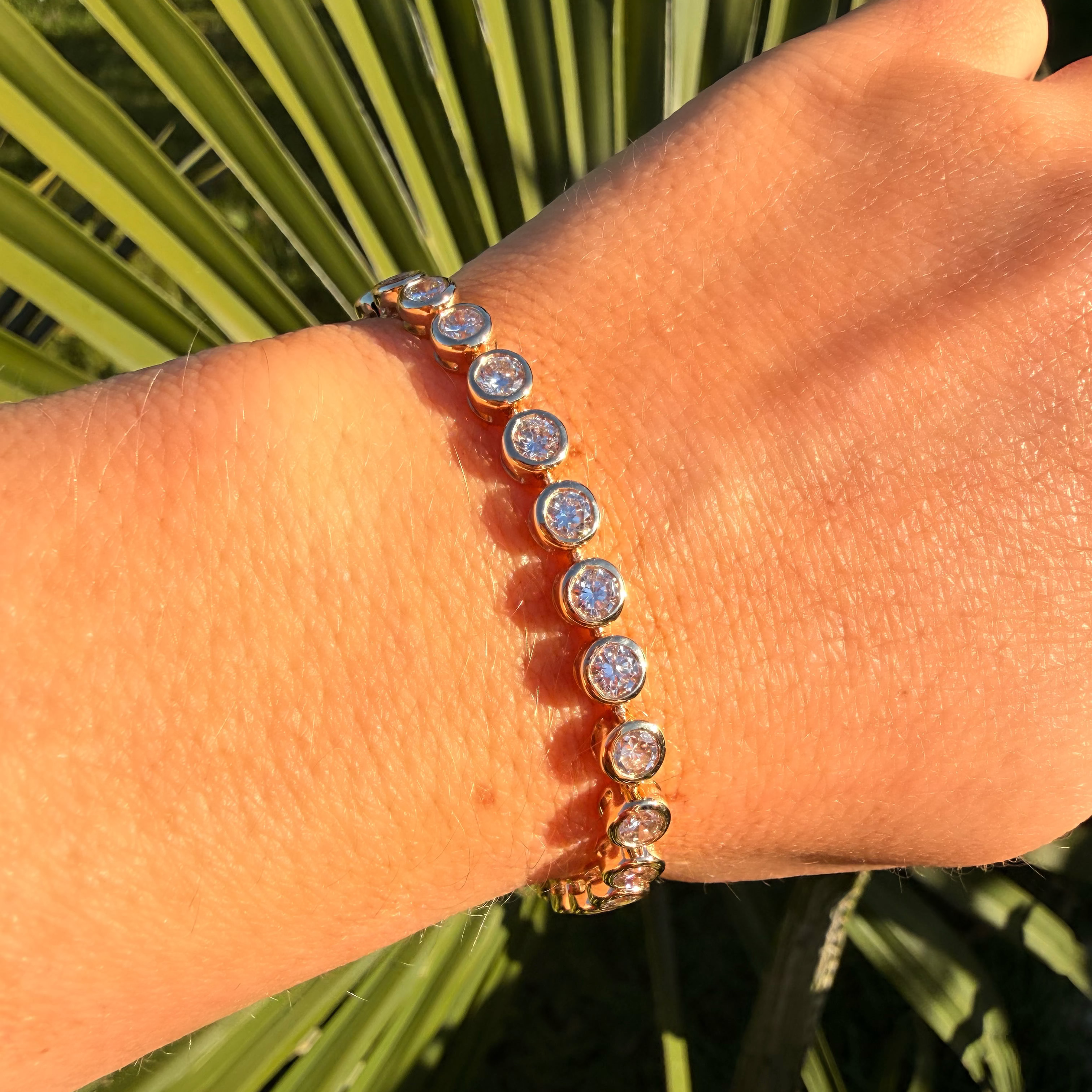 Bracelet with small round crystals on a wrist against a green leafy background