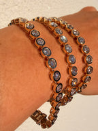 Rose gold bracelet with clear stones on a wrist against a neutral background