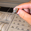 Person holding a diamond ring with a jewelry box in the background