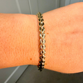 Gold chain bracelet on a wrist with a neutral background