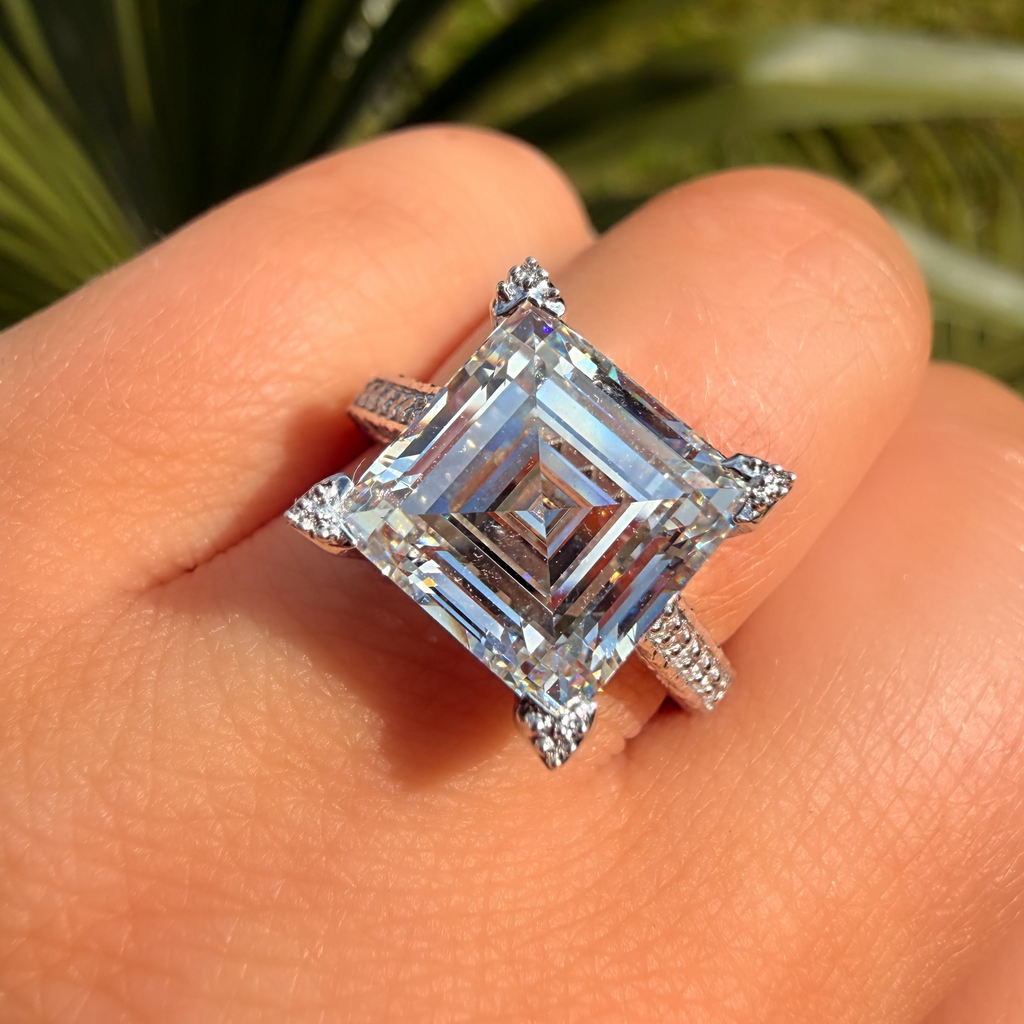 Silver ring with a large diamond on a hand, with greenery in the background
