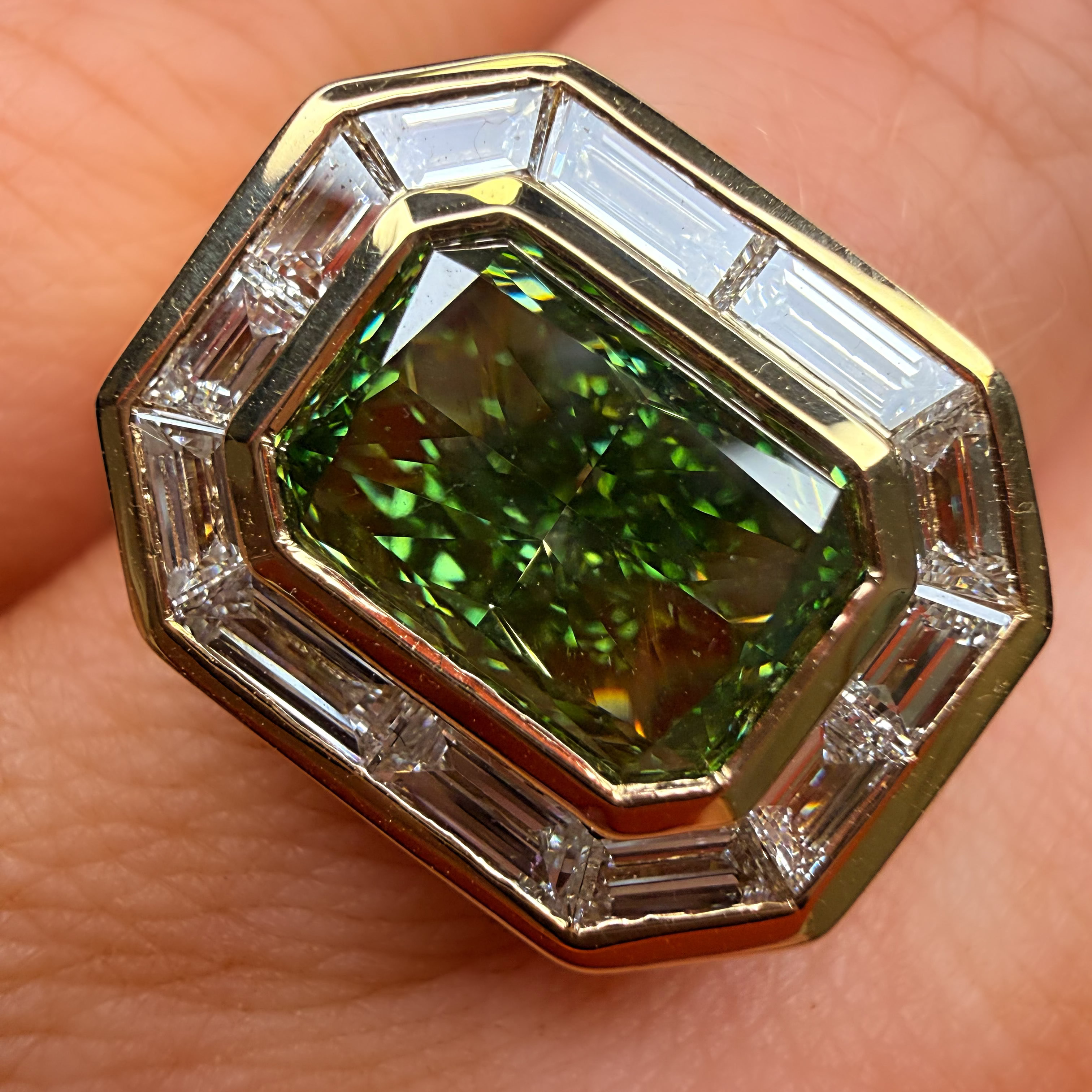 Gold ring with a green gemstone held on a person's finger
