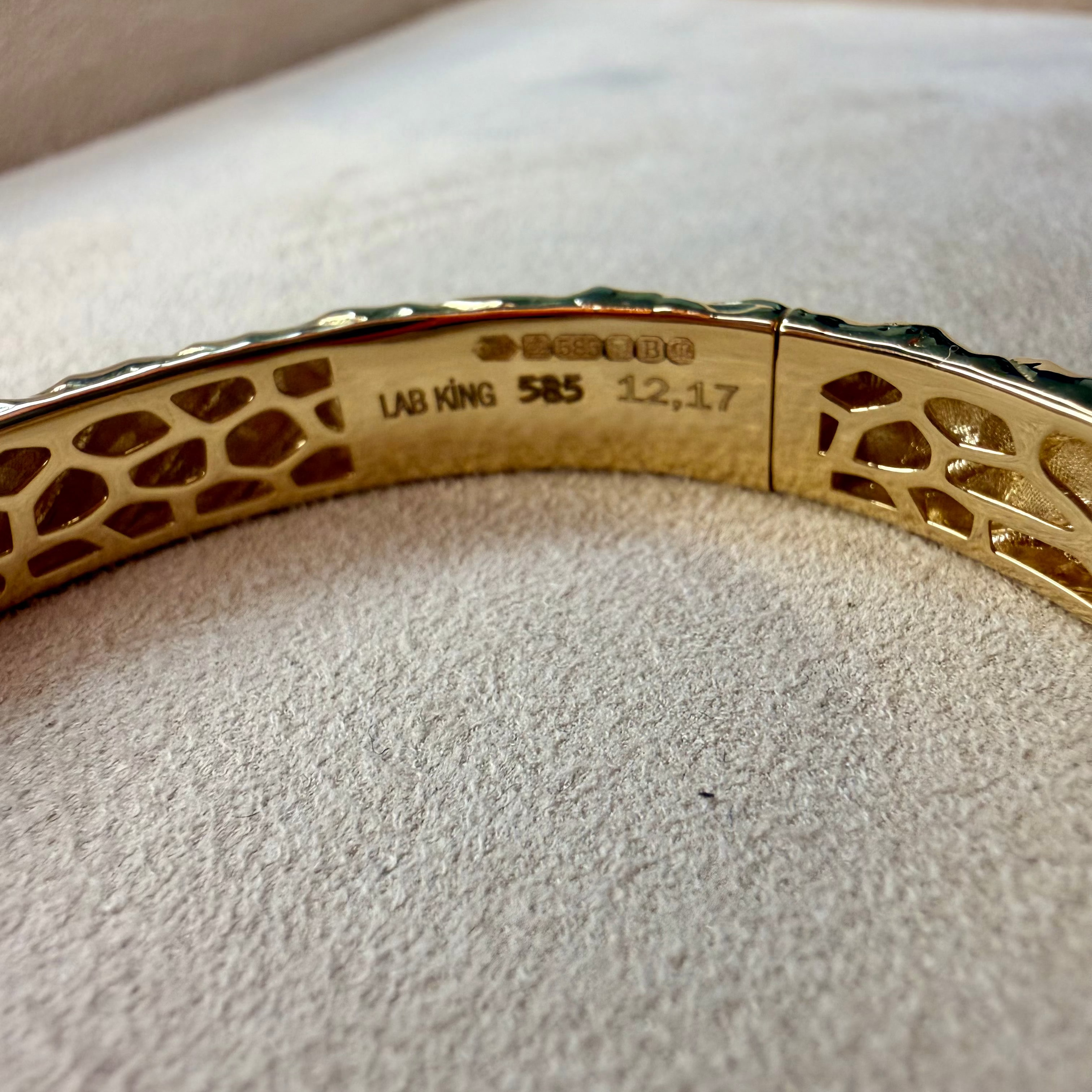 Gold bracelet with engraved details on a textured surface