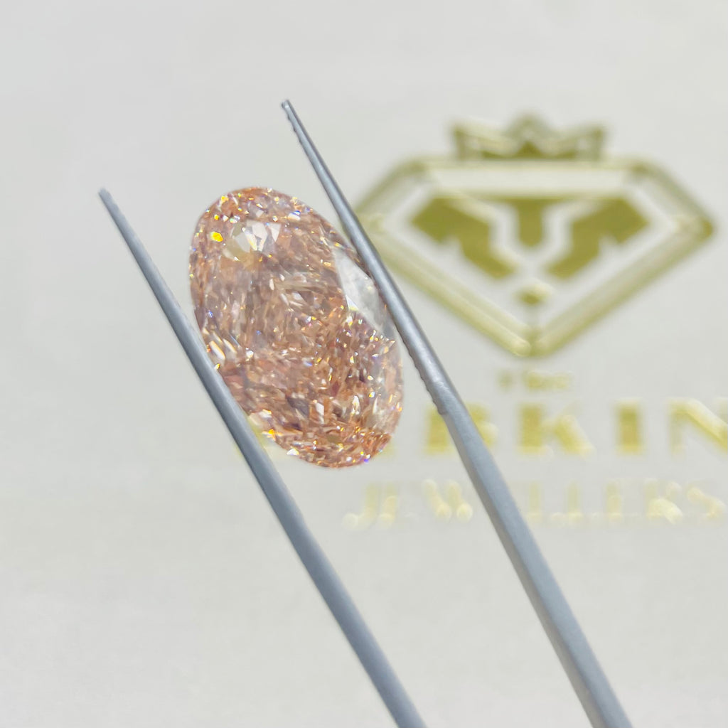 Diamond held by tweezers with a brand logo in the background