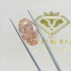 Diamond held by tweezers with a brand logo in the background