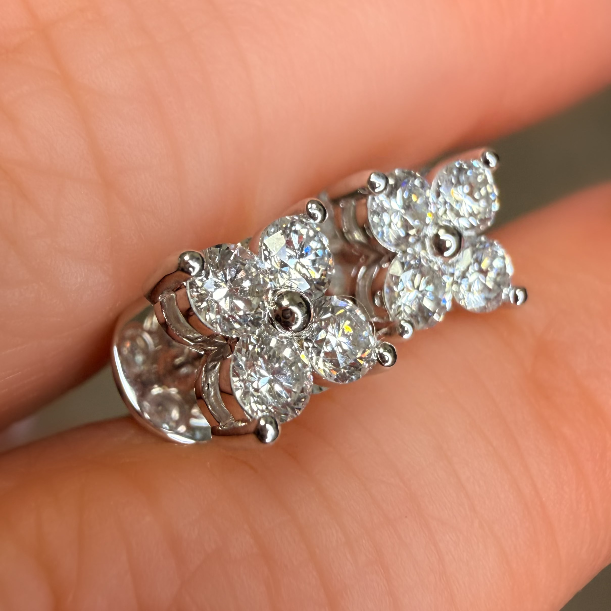 Diamond earrings held between fingers against a neutral background