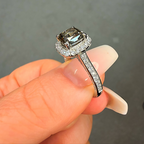 Diamond ring held between fingers against a neutral background