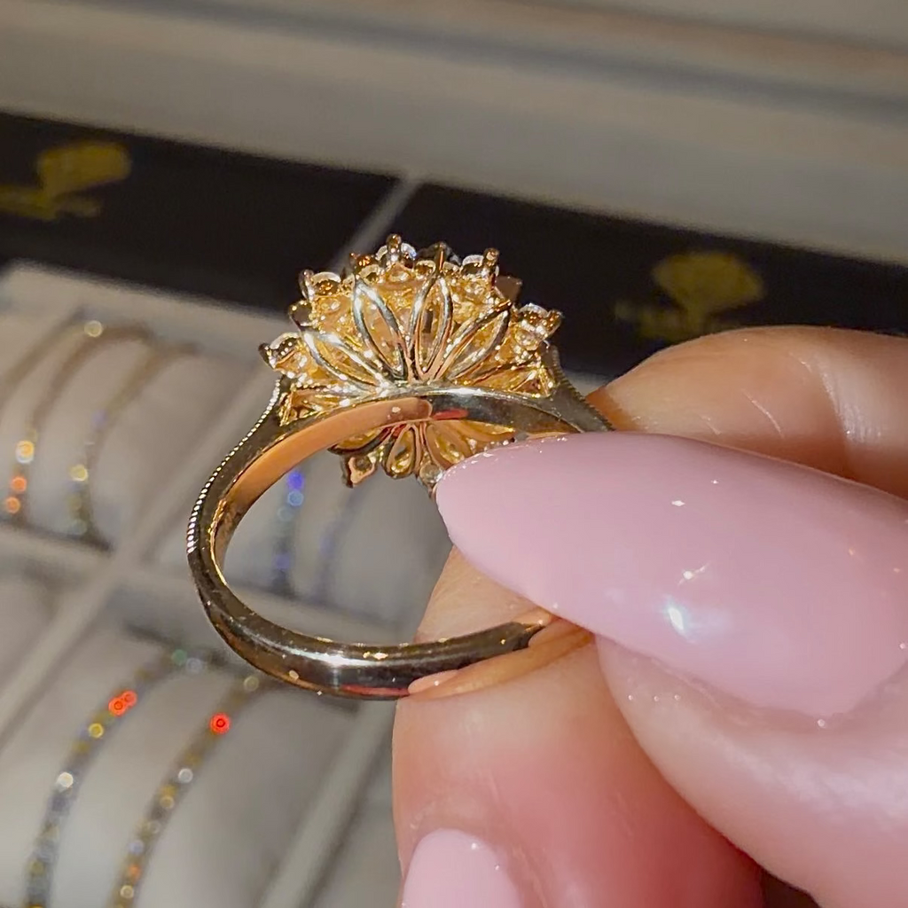 Gold ring with a star-shaped design held by a hand, with a blurred background