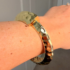 Gold bracelet on a wrist with a neutral background