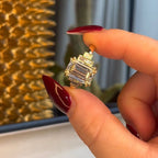 Gold ring with a large diamond held by a hand against a textured gold and white background