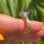 Gold ring with a diamond on a finger against a green leafy background