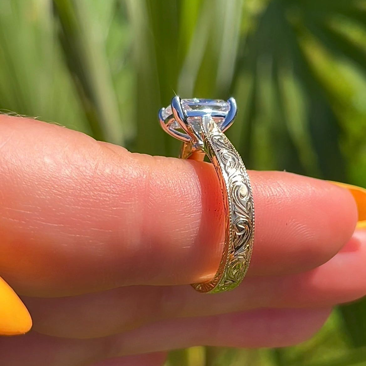 Gold ring with a diamond on a finger against a green leafy background