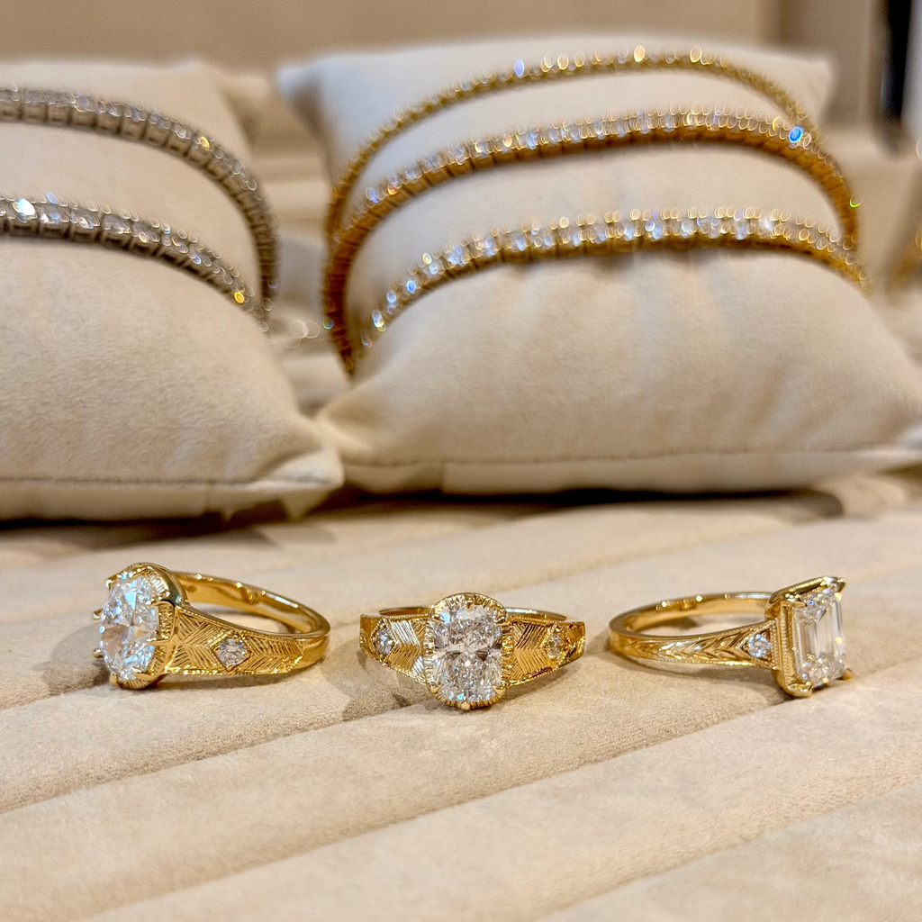 Three gold rings with diamond accents on a beige cushion