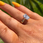 Hand wearing a diamond ring with a blurred green background