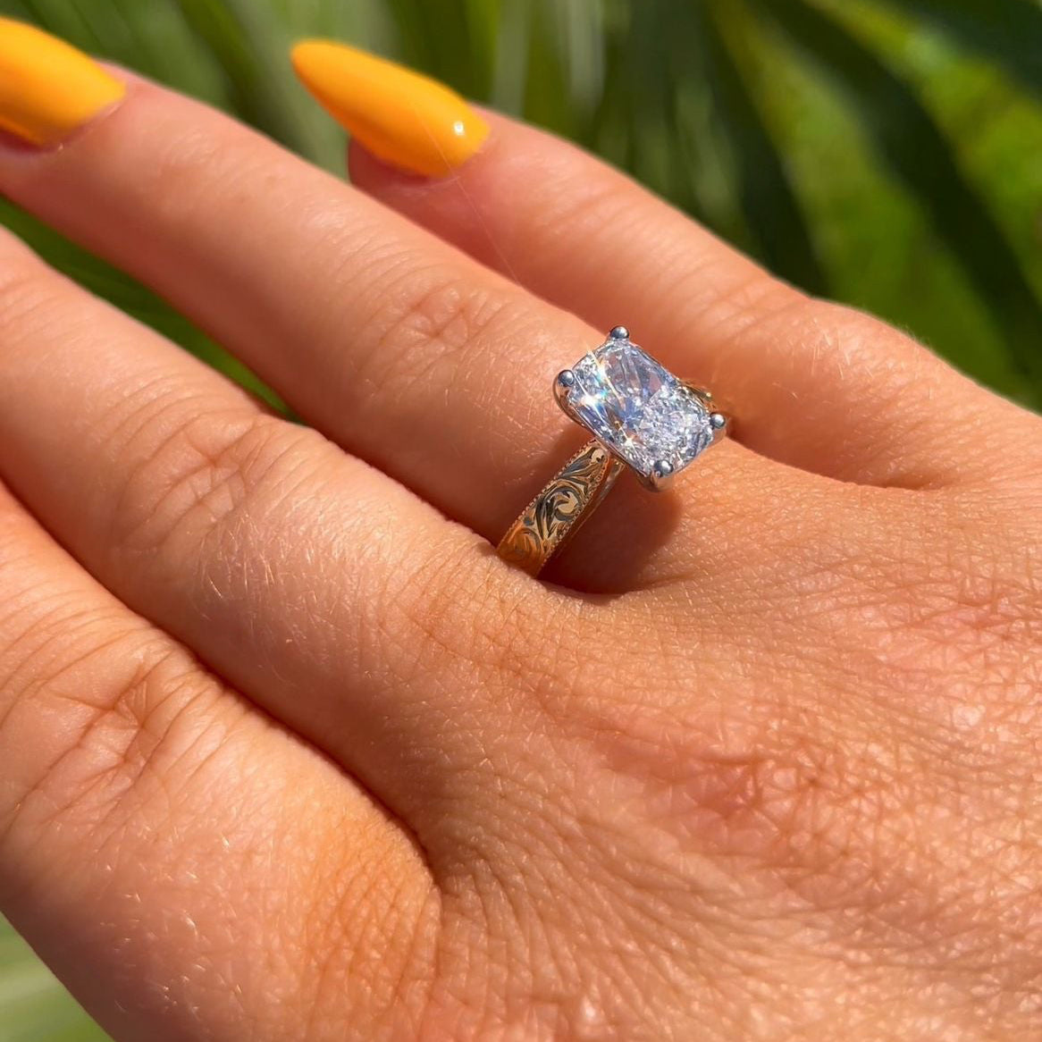 Hand wearing a diamond ring with a blurred green background