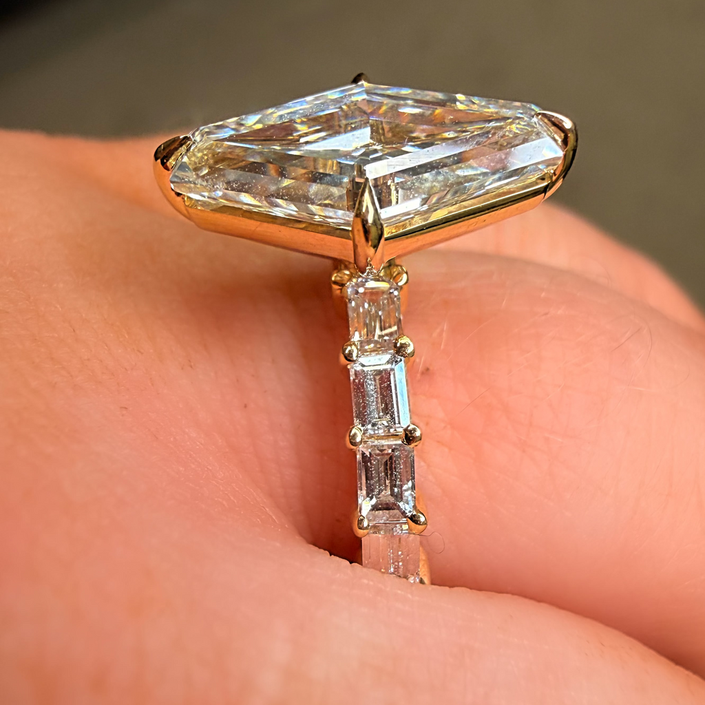 Gold ring with a large diamond and smaller baguette diamonds on a finger