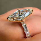 Gold ring with a large diamond and smaller baguette diamonds on a finger.