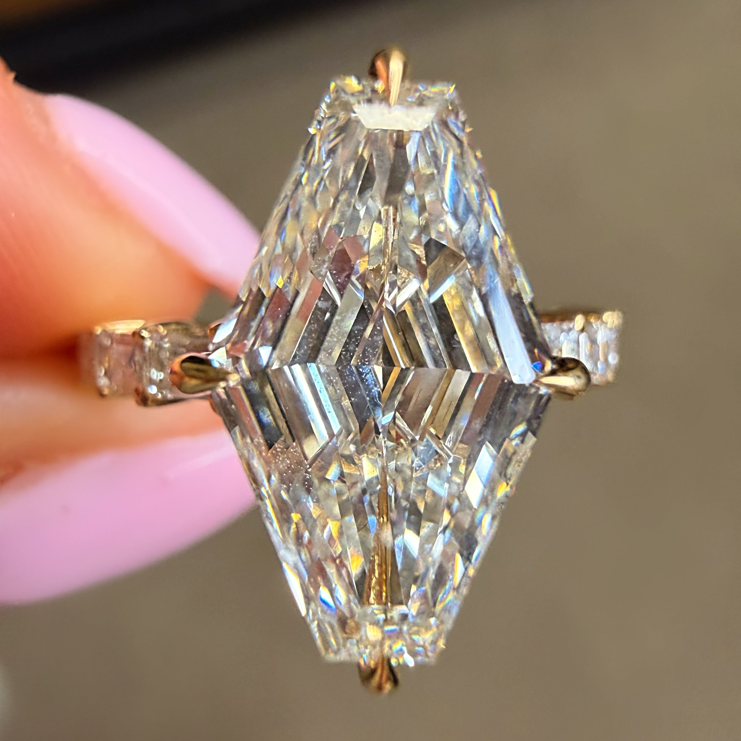 Diamond ring held by a hand with a neutral background
