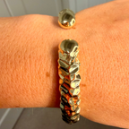 Gold bracelet on a wrist with a neutral background