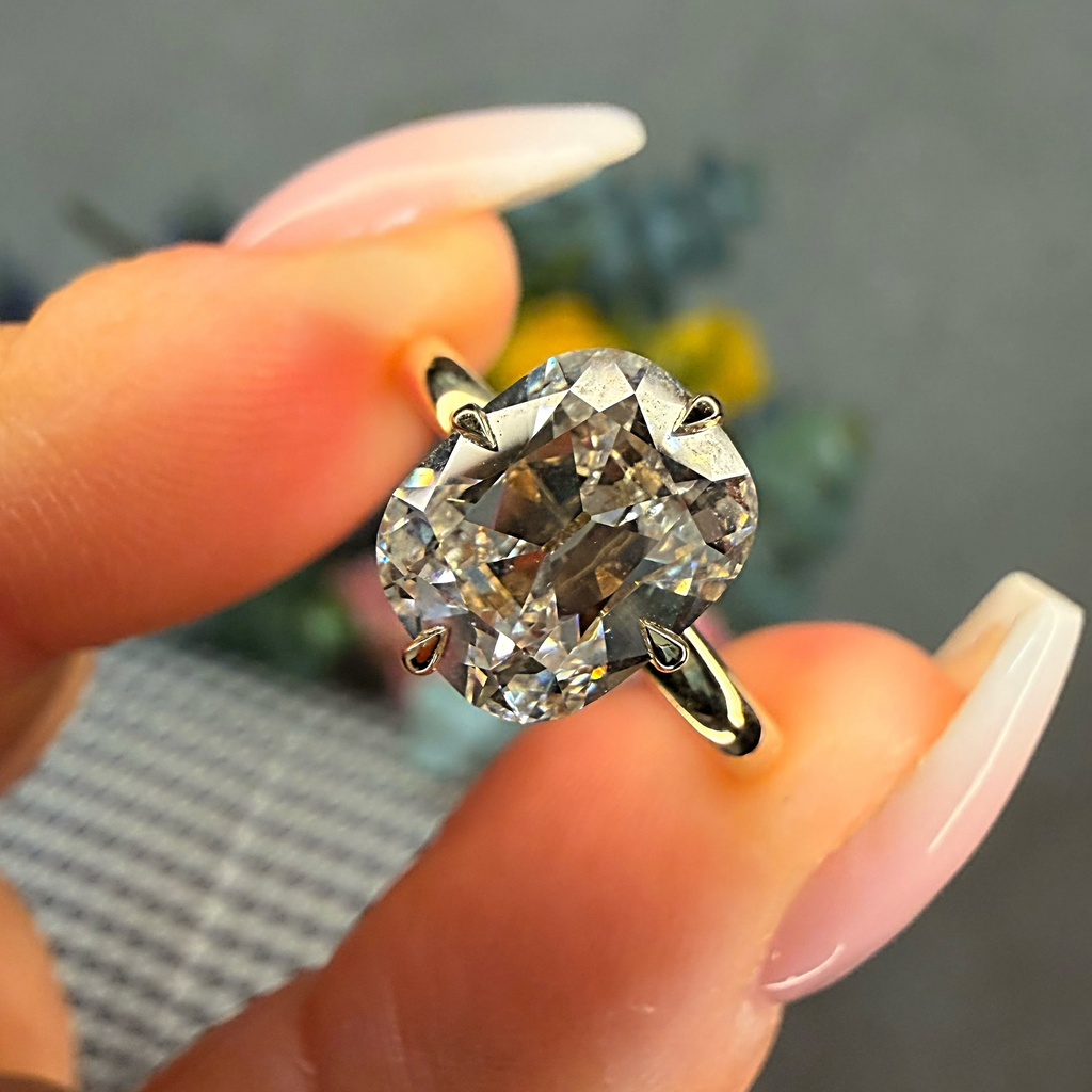 Diamond ring held between fingers with a blurred background